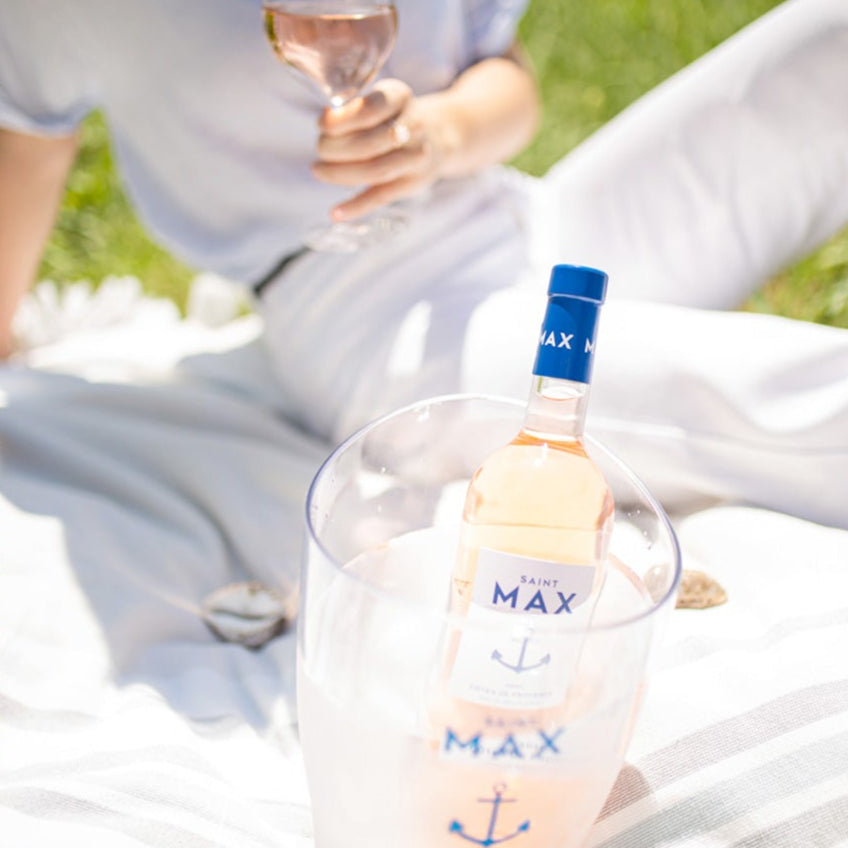 Load image into Gallery viewer, Lifestyle image of a bottle of Saint Max Cotes De Provence Rose in summer setting with man enjoying a picnic