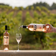 Load image into Gallery viewer, Person pouring AIX wine into a glass with vineyard in the background