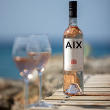 Load image into Gallery viewer, Bottle of AIX rosé wine with a glass on a wooden table by the sea.