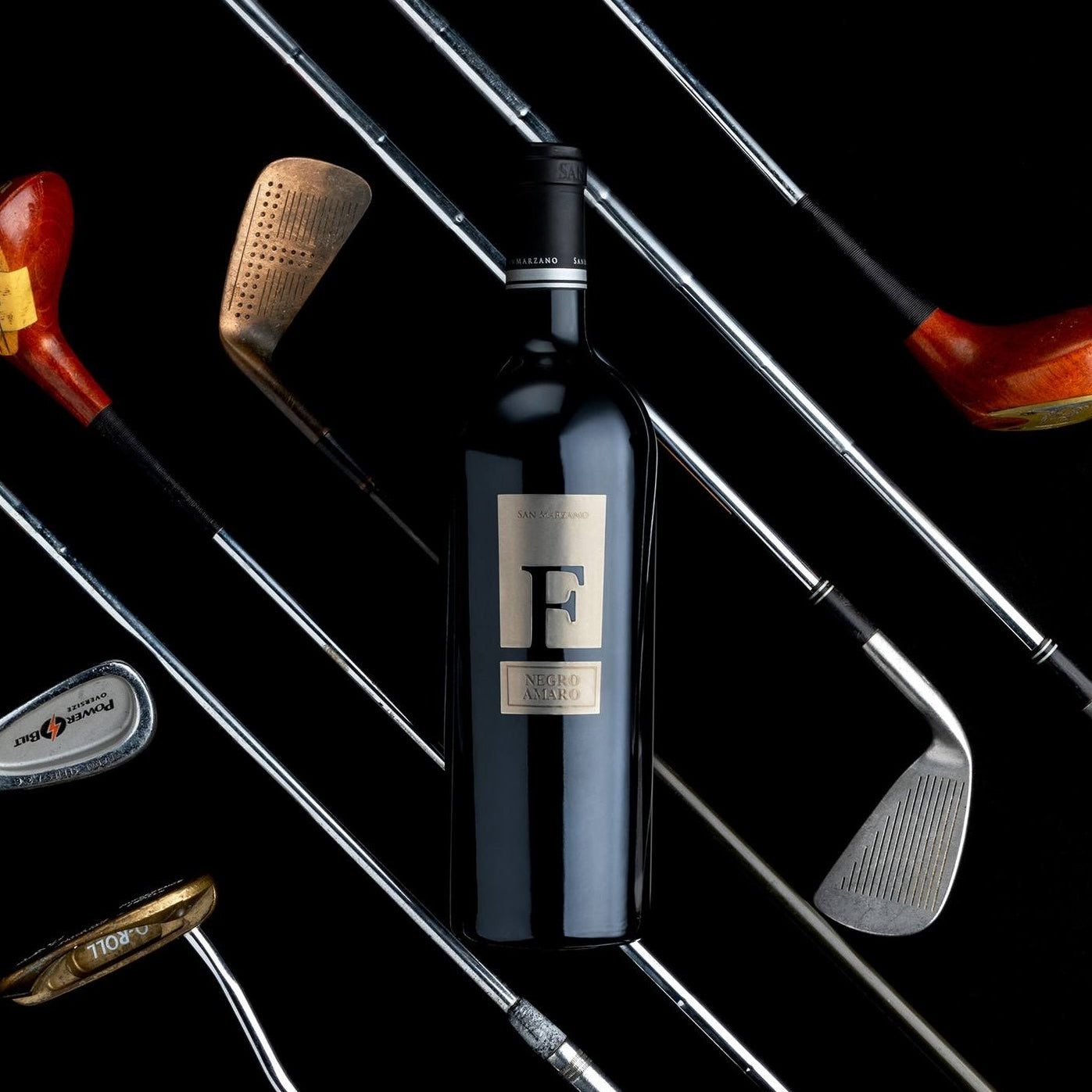 Load image into Gallery viewer, A bottle of San Marzano F Puglia Negroamaro red wine with gold clubs in background