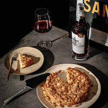 Load image into Gallery viewer, Bottle and glass of Sandeman wine with a slice of cake on a dark surface