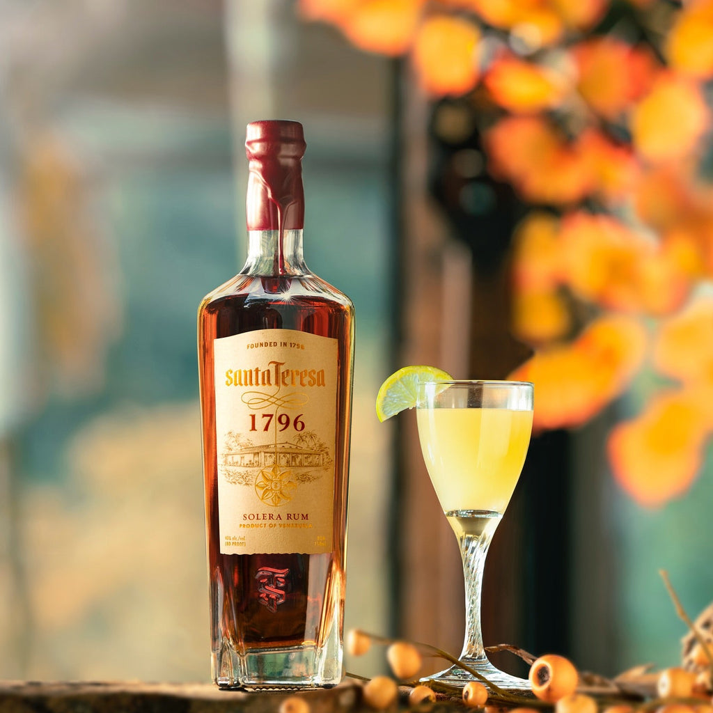 Bottle of Santa Teresa 1796 rum with a cocktail garnished with a lime wedge on a decorative surface.