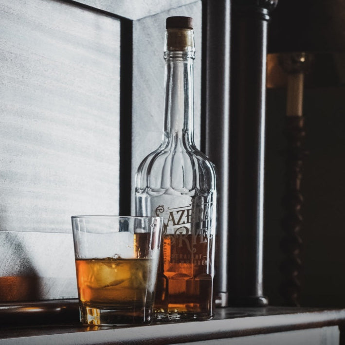 Load image into Gallery viewer, Bottle of whiskey with a glass of whiskey on a bar counter.