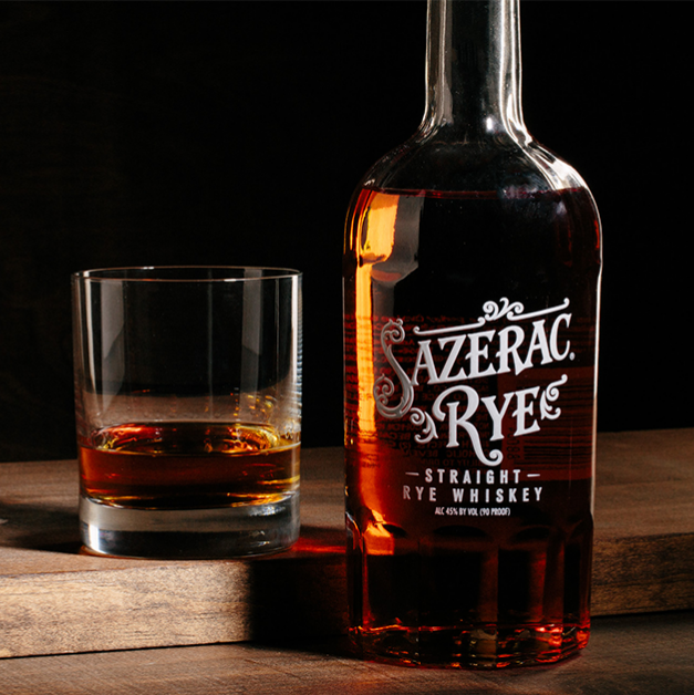 Load image into Gallery viewer, Sazerac Rye whiskey bottle and glass on a wooden surface with a dark background