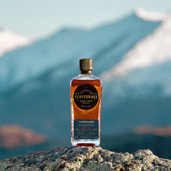 Bottle of Scapegrace Vanguard Single Malt Whisky on a rocky outcrop with mountains in the background