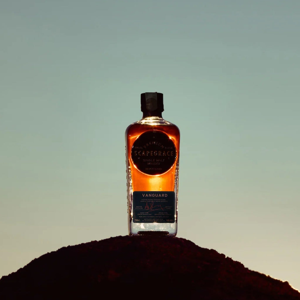Bottle of Scapegrace Vanguard Single Malt Whisky on a small hill with a gradient sky