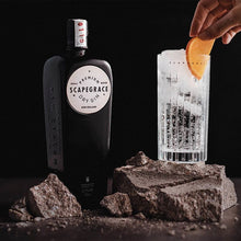 Load image into Gallery viewer, Scapegrace gin bottle with a cocktail being prepared on a dark background