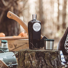 Load image into Gallery viewer, Bottle of Scapegrace gin on a wooden stump with camping gear in the background