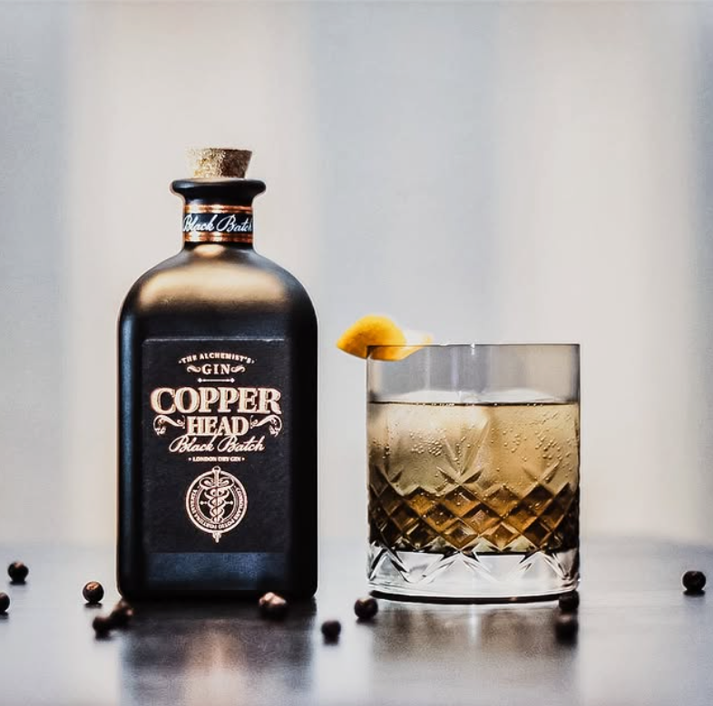Load image into Gallery viewer, Copperhead Black Batch Gin bottle with a glass of cocktail on a reflective surface
