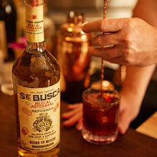 Load image into Gallery viewer, Bottle of Se Busca Mezcal Reposado with a glass of mezcal on a bar counter.