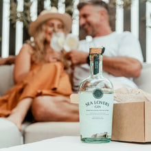 Load image into Gallery viewer, Bottle of Sea Lovers Gin on a table with a blurred background of a couple sitting on a couch.