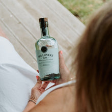 Load image into Gallery viewer, Woman holding a bottle of Sea Lovers Gin in a relaxed outdoor setting