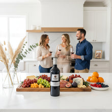 Load image into Gallery viewer, People enjoying a bottle of Shingleback D Block Reserve Cabernet Sauvignon wine in a kitchen with a cutting board with fruits and cheese.