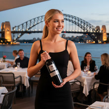 Load image into Gallery viewer, Woman holding a bottle of Shingleback D Block Reserve Cabernet Sauvignon wine in a restaurant with a bridge in the background
