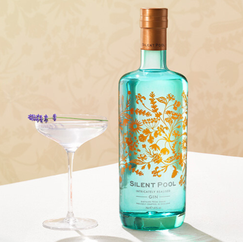 Load image into Gallery viewer, Bottle of Silent Pool gin bottle with floral design next to a martini glass on a neutral background.