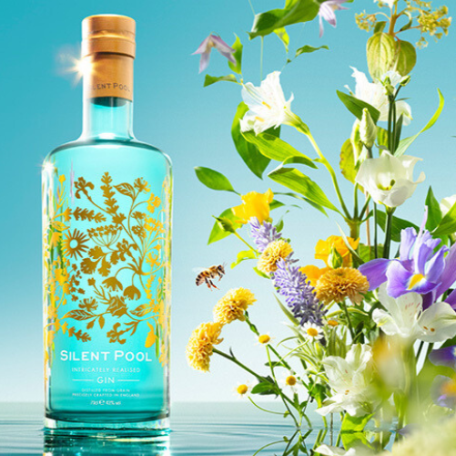 Load image into Gallery viewer, Bottle of Silent Pool with floral design and flowers in the background