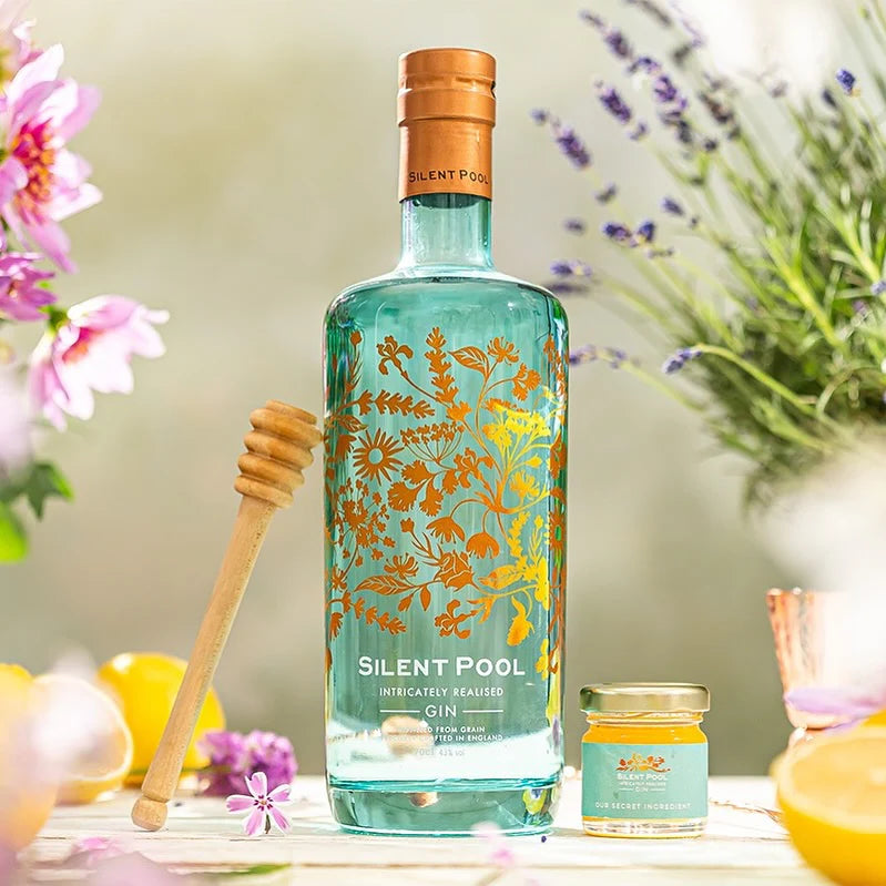 Load image into Gallery viewer, A bottle of gin and some flowers in the background.