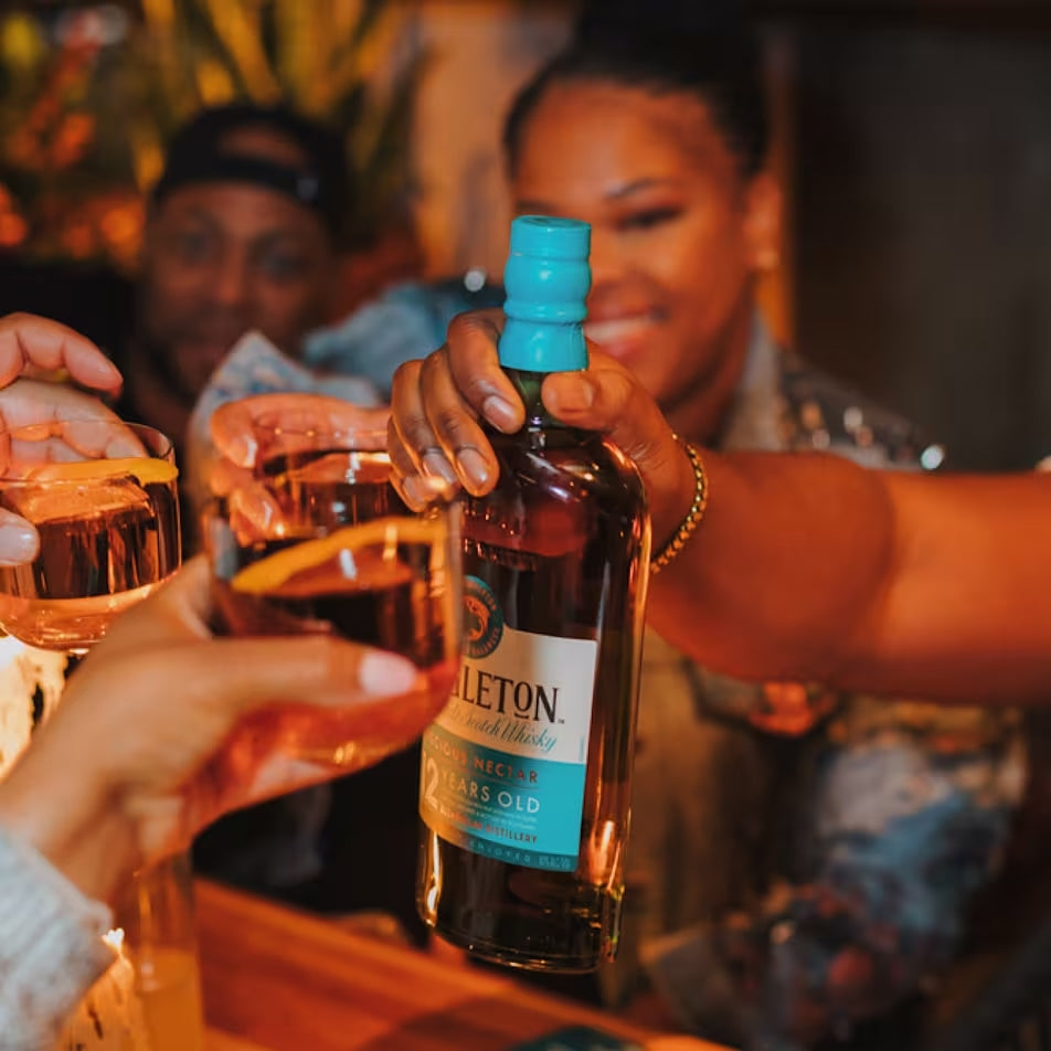 Load image into Gallery viewer, People toasting with a bottle of Singleton of Dufftown 12 Year Old Single Malt Scotch Whisky in a social setting.