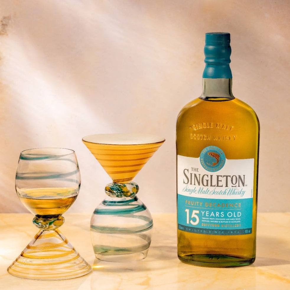 Load image into Gallery viewer, A Singleton of Dufftown 15 Year Old Single Malt Scotch Whisky bottle with two glasses on a wooden surface