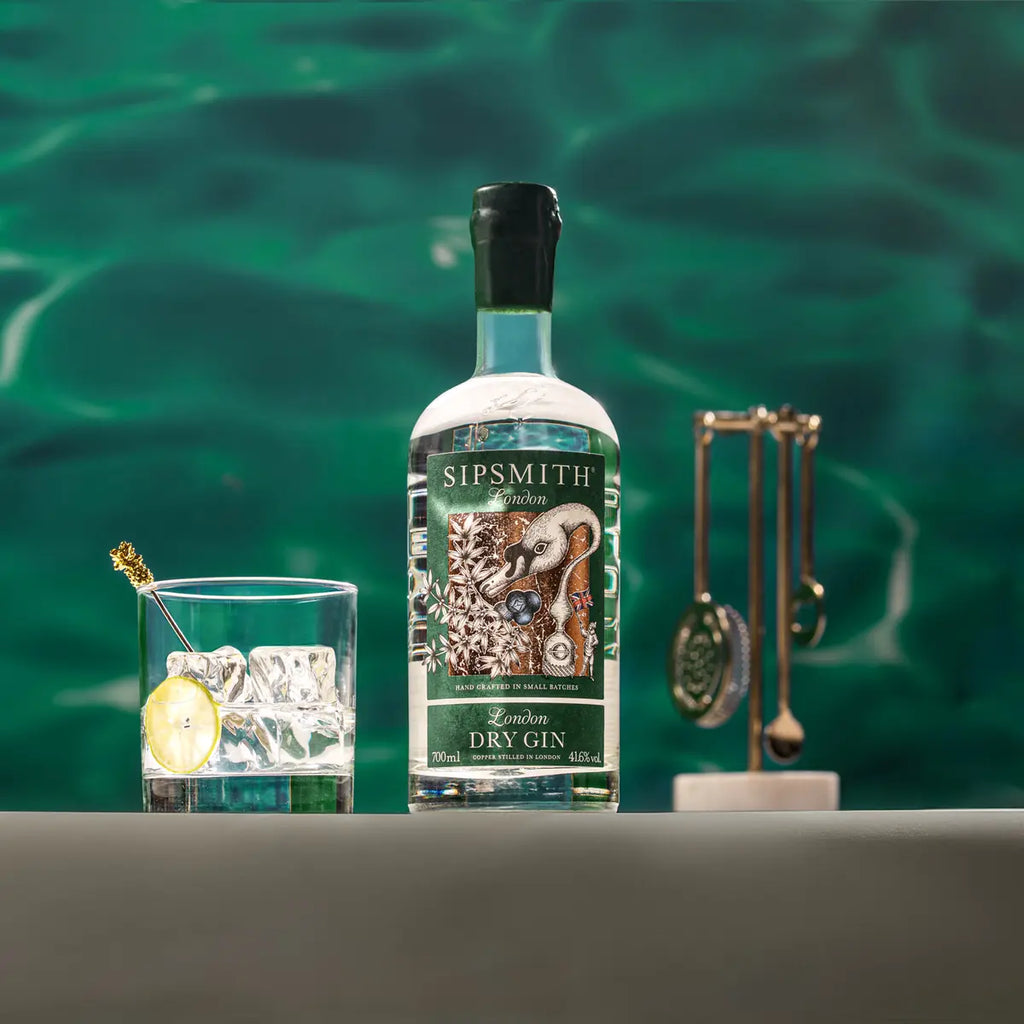 Sipsmith gin bottle with a glass of cocktail and decorative spoons on a green background