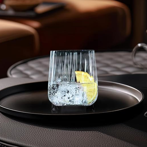 Clear glass with lemon wedge on a black tray, Spiegelau logo visible