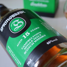 Load image into Gallery viewer, Springbank 15-year-old single malt Scotch whisky bottle with a glass of whisky in the background.