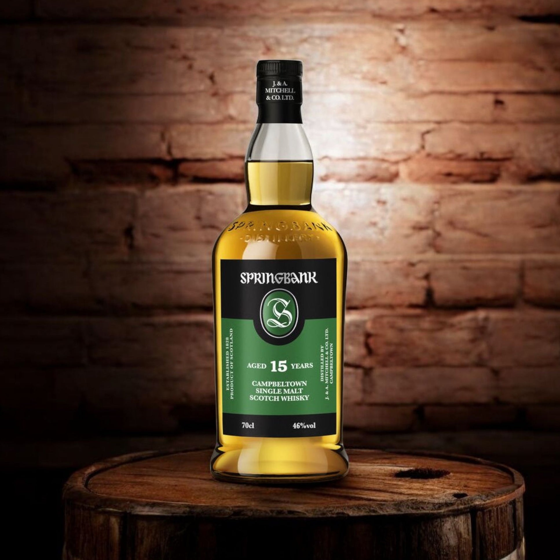 Load image into Gallery viewer, A bottle of Springbank 15 Years Old Single Malt Scotch Whisky stands on a wooden barrel against a rustic brick wall background.