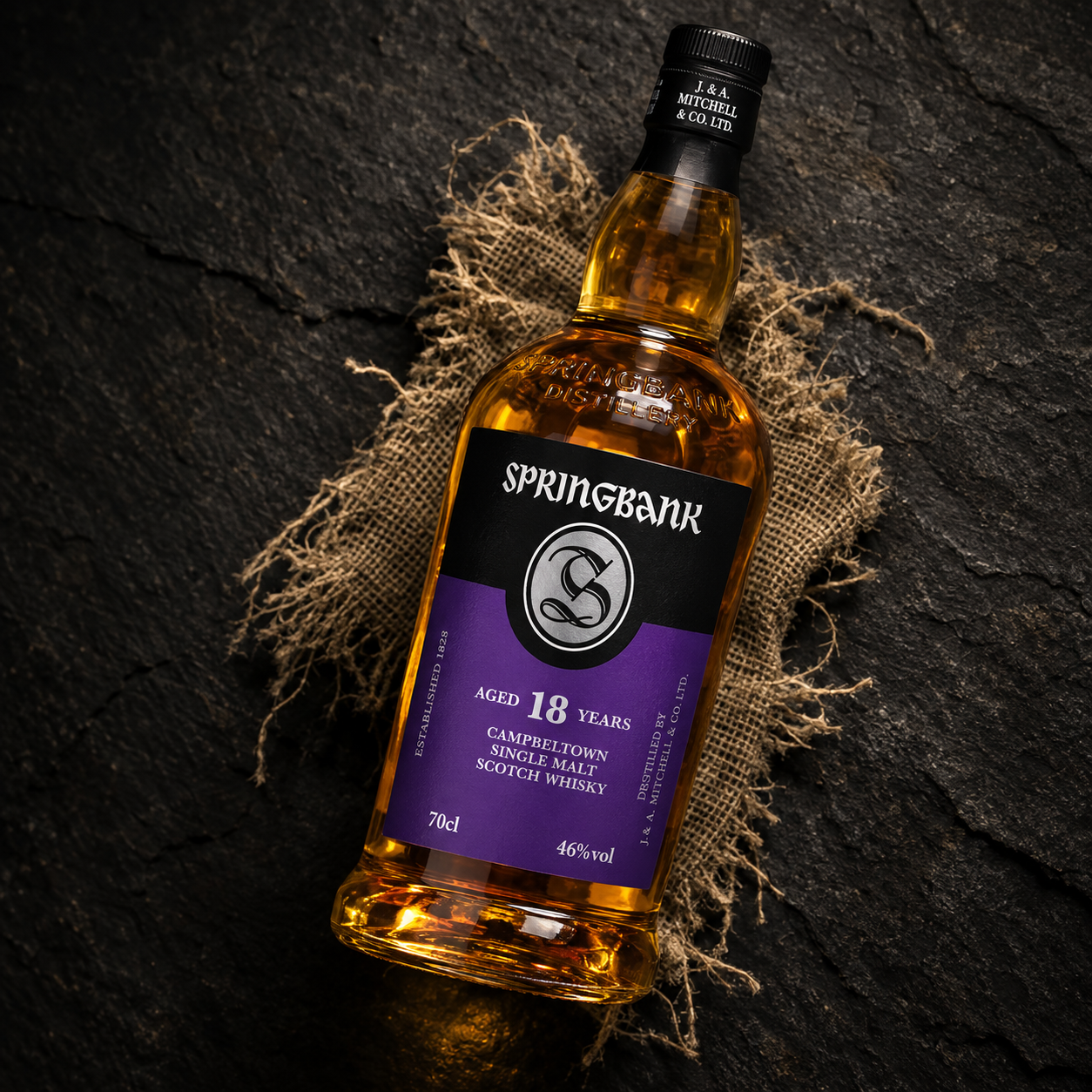 Load image into Gallery viewer, A bottle of Springbank 18 Years Old single malt Scotch whisky, presented diagonally on a dark textured slate background with a rustic burlap sack.