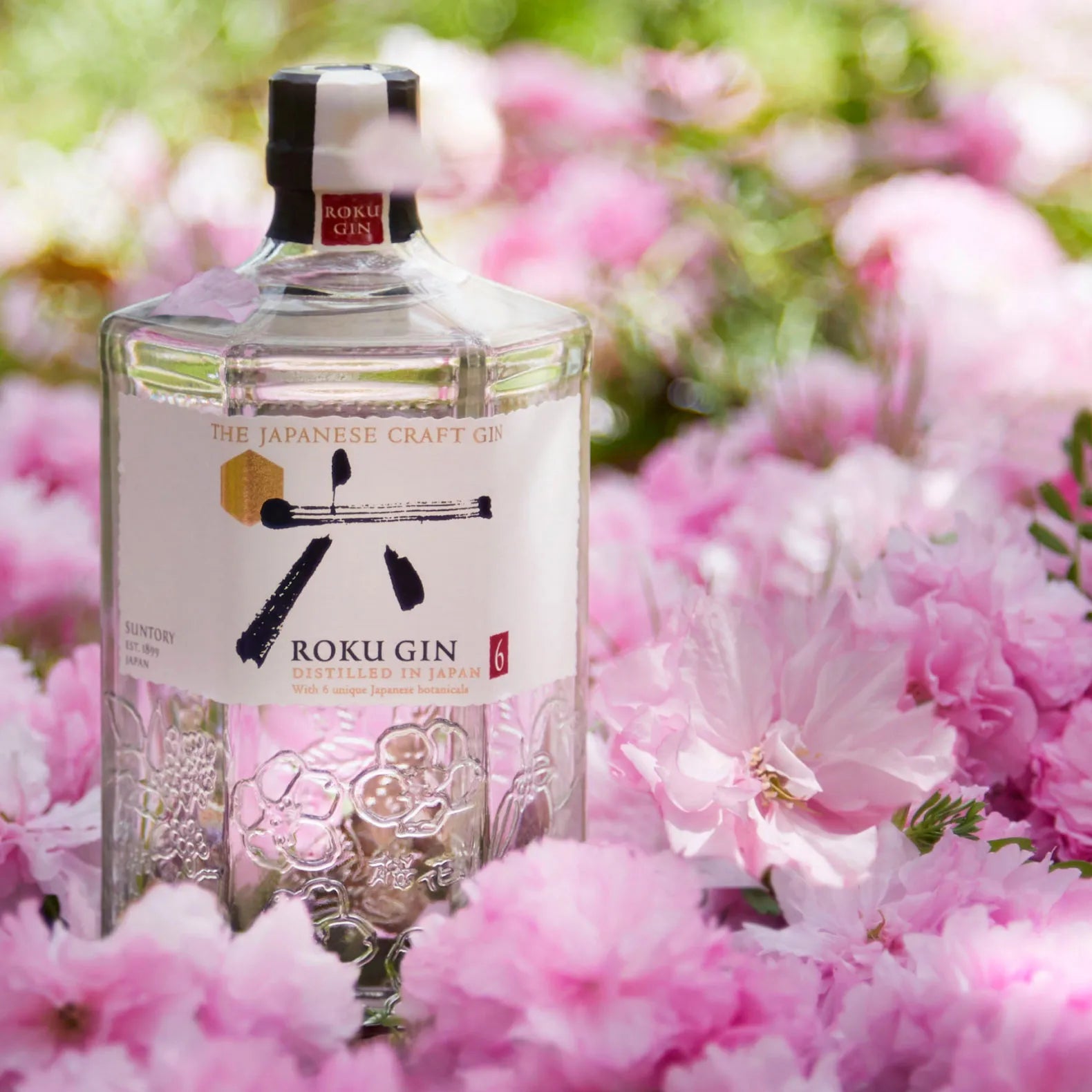 Load image into Gallery viewer, Roku Gin bottle surrounded by pink flowers