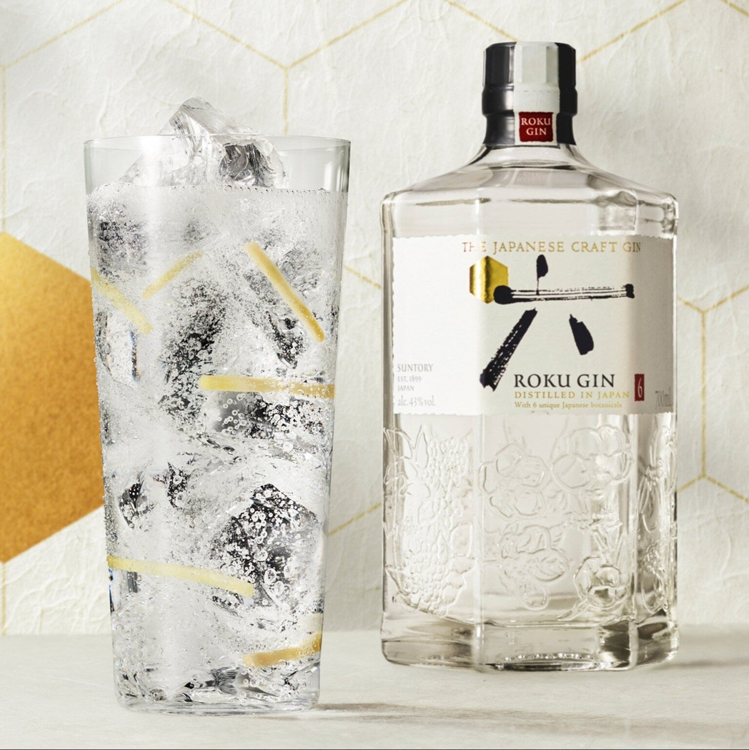 Load image into Gallery viewer, Roku Gin bottle with a glass of gin and tonic on a decorative background