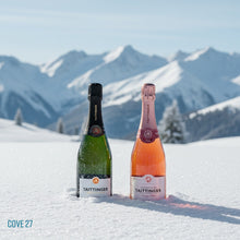 Load image into Gallery viewer, Two Taittinger champagne bottles in the snow with mountains in the background