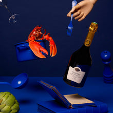 Load image into Gallery viewer, Bottle of champagne, lobster, and other items on a blue background