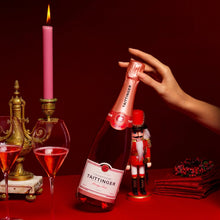 Load image into Gallery viewer, Bottle of Taittinger champagne being held on a red table with decorative elements.