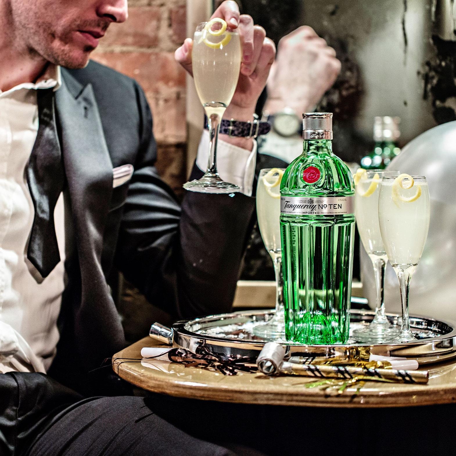 Load image into Gallery viewer, Person in formal attire pouring a drink, with a bottle of Gin and Tonic on a tray.