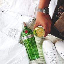Load image into Gallery viewer, Person holding a bottle of Tanqueray No. Ten gin with a lime wedge on a wooden surface.