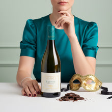 Load image into Gallery viewer, A woman in a teal coloured dress sitting behind a bottle of A bottle of Te Mata Elston Chardonnay, with some chocolate next to it.