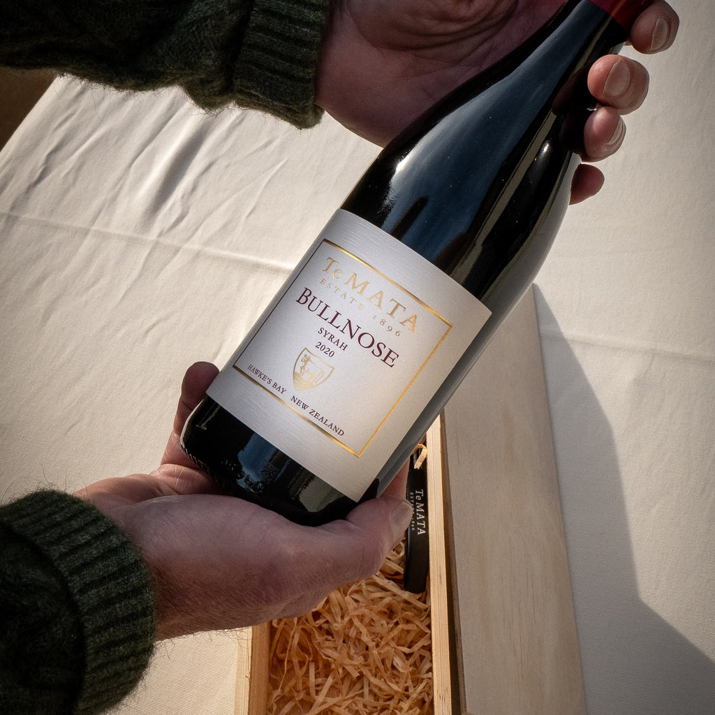 Person holding a bottle of Te Mata Estate Bullnose Syrah wine with a neutral background