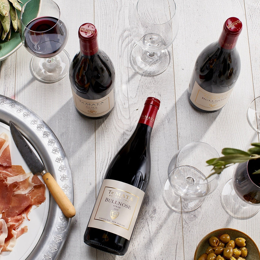 Te Mata Estate Bullnose Syrah Wine bottles with labels on a table with glasses and food