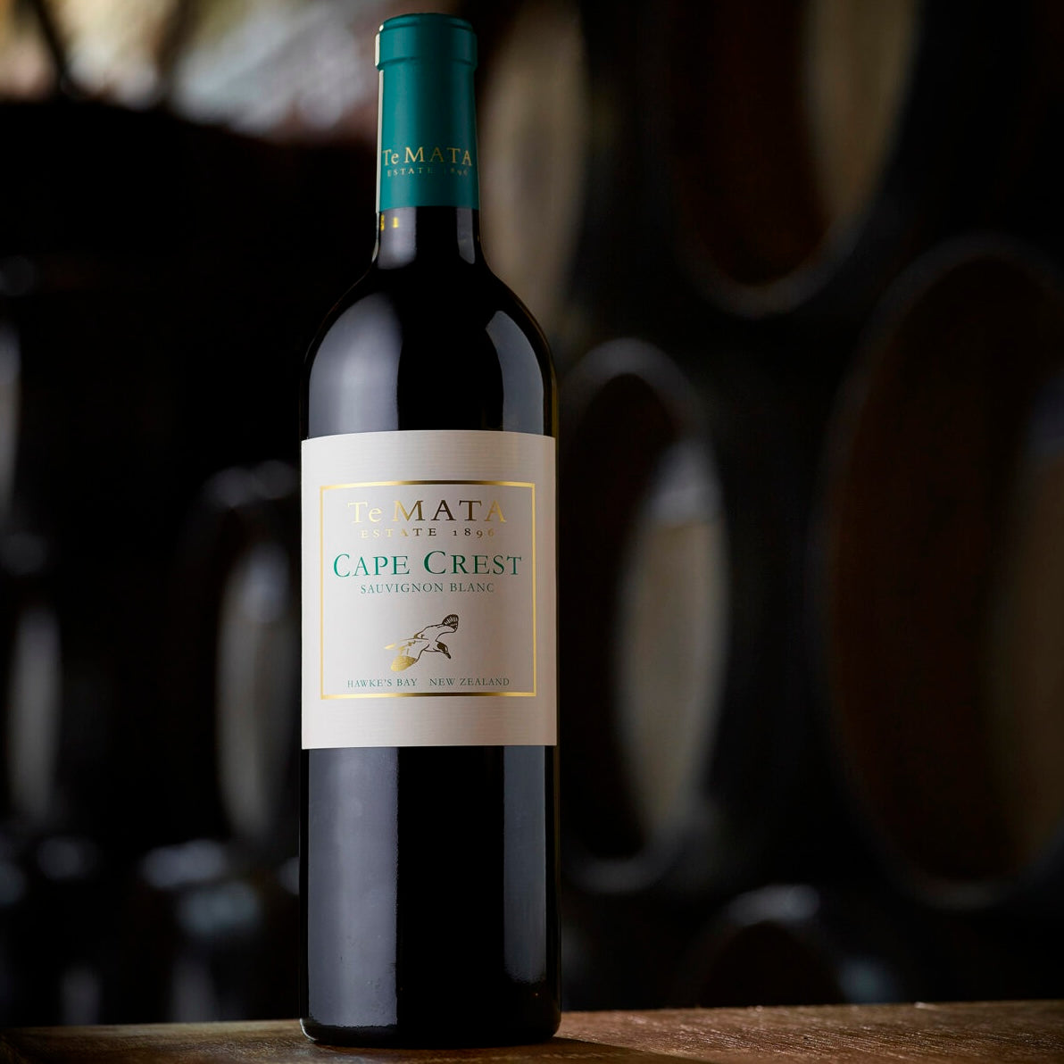 Load image into Gallery viewer, A bottle of Te Mata Estate Cape Crest Sauvignon Blanc with some barrels in the background