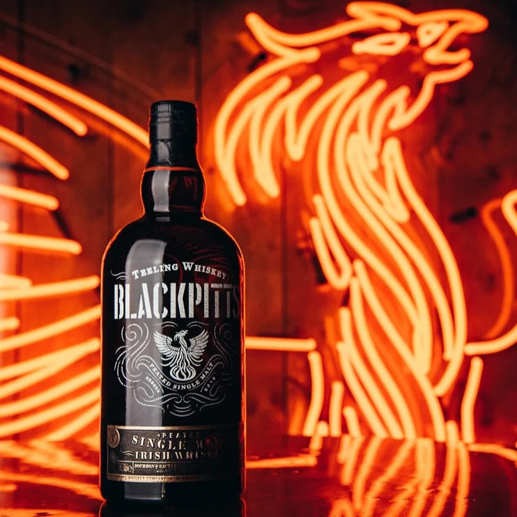 Load image into Gallery viewer, A bottle of Teeling Whiskey on a table infront of a neon sign