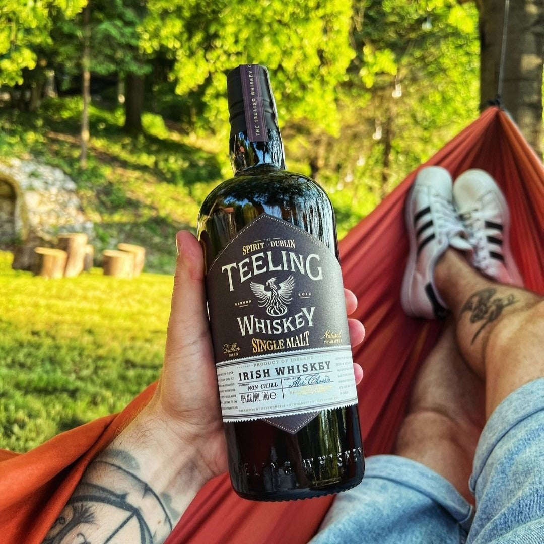 Load image into Gallery viewer, A man relaxing holding a bottle of Teeling Single Malt Whiskey in his hand