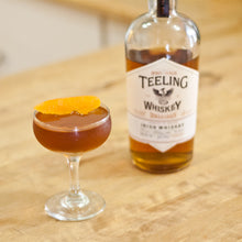 Load image into Gallery viewer, Teeling whiskey bottle with a cocktail on a wooden surface