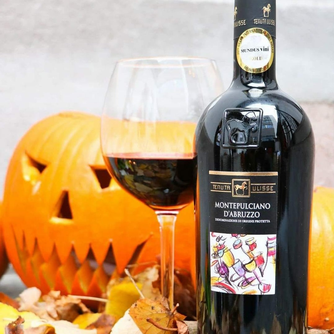 Load image into Gallery viewer, A bottle of Tenuta Ulisse Montepulciano d'Abruzzo next to a glass of wine and a Halloween Pumpkin