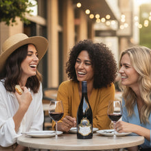 Load image into Gallery viewer, Three women enjoying a bottle of Terra-Sancta-Estate-Jacksons-Block-Pinot-Noir and food at an outdoor restaurant.