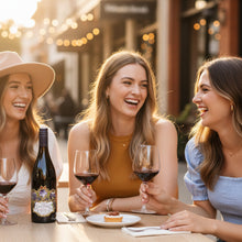 Load image into Gallery viewer, Three women enjoying a bottle of Terra-Sancta-Pinot-Noir wine and dessert outdoors in a casual setting