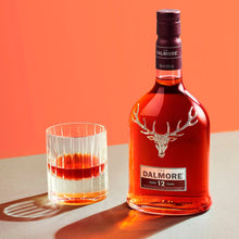 Load image into Gallery viewer, Dalmore 12 year old whisky bottle with a glass of whisky on an orange background