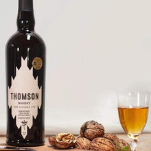 Load image into Gallery viewer, Bottle of Thomson Manuka Smoke Whisky with a glass of whisky and snacks on a wooden surface.