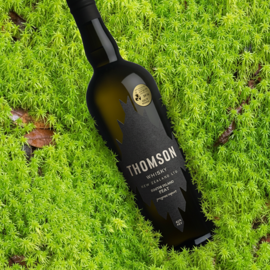 Bottle of Thomson peated whisky on a green moss background