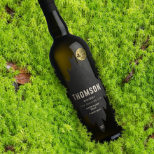 Load image into Gallery viewer, Bottle of Thomson peated whisky on a green moss background
