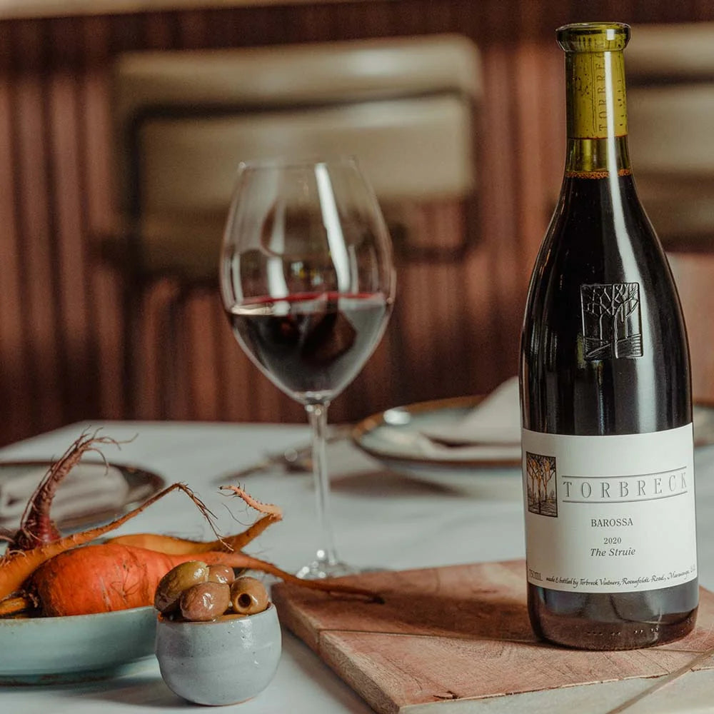 Load image into Gallery viewer, Bottle of Torbreck wine on a table with a glass and food in the background